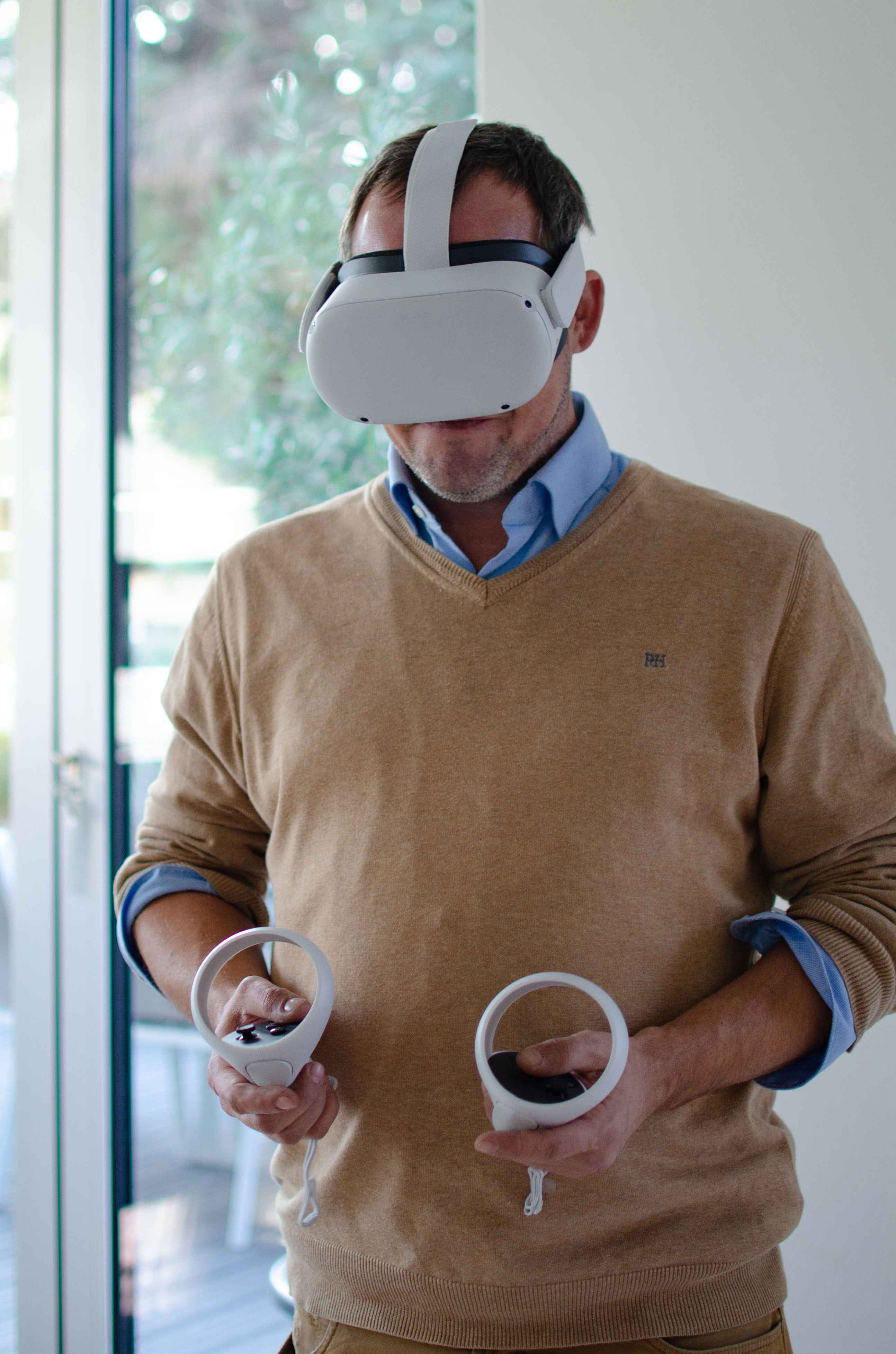 Mann mit einer VR-Brille auf und zwei VR-Controllern in der Hand